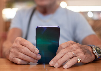 Close up on senior man sitting holding mobile phone. Elderly male using modern technology for online connection