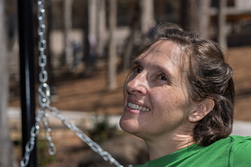 Happy woman looks up while sitting on a bench in a park on a sunny day in spring