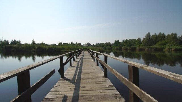 
Old wooden bridge over the lake in a village at sunny day dolly wide angle shot

