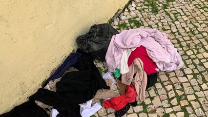 Colorful clothes scattered on cobblestone, urban cleanup, recycling concept, environmental...