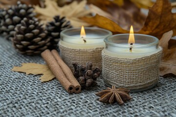 Cozy autumn decor with candles, spices, and natural elements on a textured surface in warm fall colors