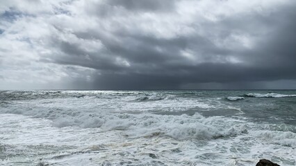 Turquoise waves crash under a moody sky, capturing stormy sea vibes and nature's power, perfect for...