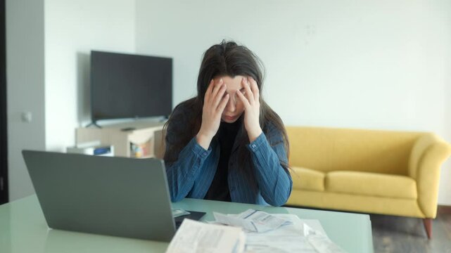 Stressed woman overwhelmed by financial issues and paperwork at home desk