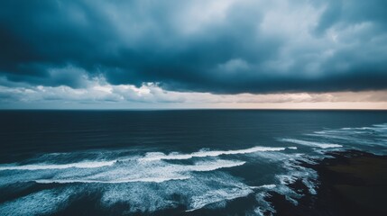 Fototapeta premium Massive waves crash against rocks in a stormy sea, while dark clouds loom overhead. The scene captures the raw energy of nature during turbulent weather conditions
