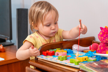 Educational fun: Toddler engrossed in fishing puzzle game, promoting cognitive skill and fine motor development, ideal for childhood education