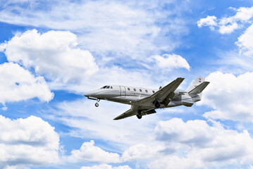 Private business plane flying under a blue sky with white clouds	