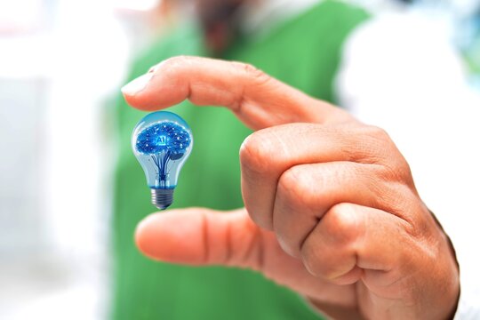 The concept of Artificial Intelligence Machine in a light bulb between hands - Powered by Adobe