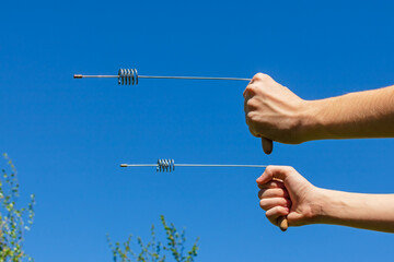 Modern dowsing with a metal L rods indicator in hands. Pair of Divining rods steel cylinder...