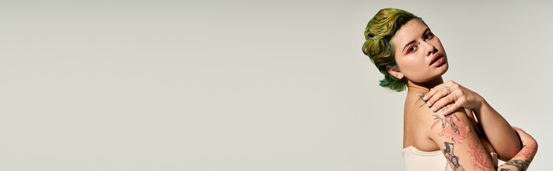 A confident young woman showcases her vibrant personality with stylish makeup and tattoos.