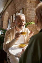 Mature couple sharing a joyful moment over coffee in a cozy cafe setting