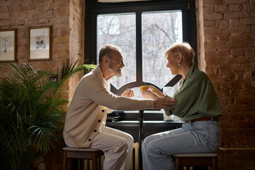 Obraz premium Mature couple enjoys a romantic date in a cozy cafe with warm ambiance