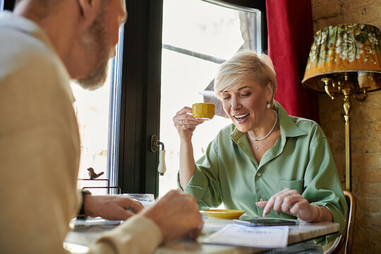 Mature couple enjoys laughter and coffee during a cozy date in a charming cafe setting