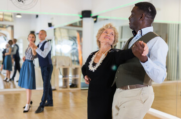 Elderly woman learning ballroom dancing in pair in dance studio