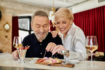 Romantic dinner between a mature couple enjoying gourmet dishes in a cozy cafe