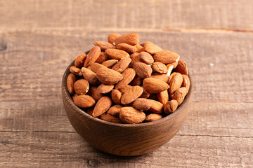 Raw peeled almonds in brown bowl