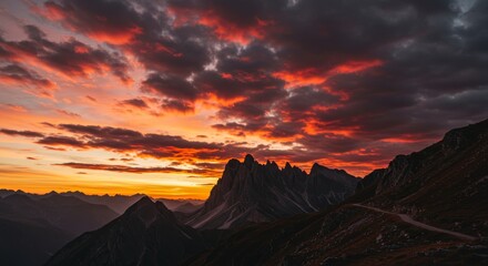 Naklejka premium Golden Hour Over Majestic Peaks - Dramatic sunset paints the sky with fiery hues, casting long shadows across rugged mountains. Symbolizing: adventure, serenity, power, beauty, hope