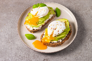Toast with avocado, soft cream cheese, rye bread and poached Egg. Wholemeal open sandwich for healthy breakfast concept