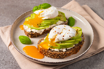 Toast with avocado, soft cream cheese, rye bread and poached Egg. Wholemeal open sandwich for healthy breakfast concept