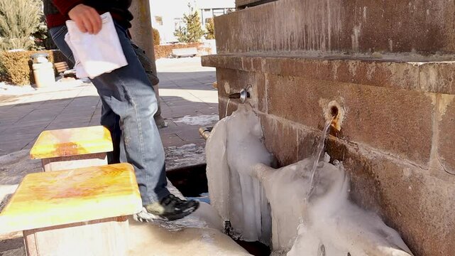 Muslim man performs ablution in freezing water at an ancient outdoor water source in Erzurum, Turkey. Ice forms around the faucets at -30&deg;C. The water left on his hair instantly freezes in the cold.