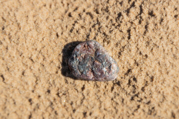 Close-Up of a Single Rock on Sandy Textured Background in Natural Light