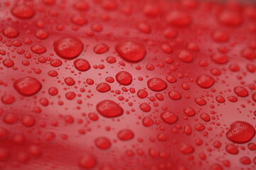 water droplets on the surface of a red shiny surface 