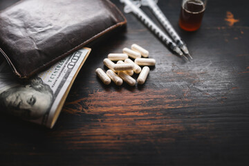 White capsules, narcotics or medicine, syringes and glass vial with substance, wallet and US dollar...