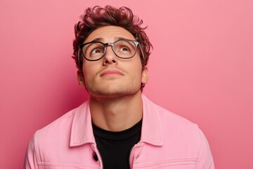 Obraz premium Young man in pink jacket gazing upward against solid pink background