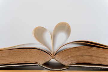 Heart from page of book for valentine's day concept with blurred bright light background and vintage tone.