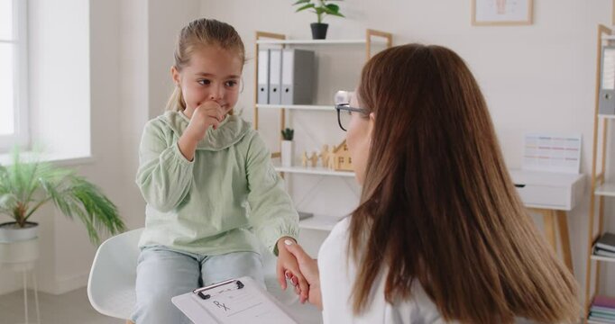 Pediatrician, otolaryngologist in white coat examines little girl kid patient, visiting modern clinic for medical care with throat pain complaints, laryngitis diagnose, contagious disease helping