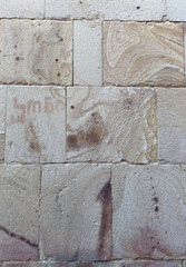 Beige sandstone church wall with large, textured bricks. Historic architecture detail, ideal as a natural stone background or rustic texture for design and creative projects.