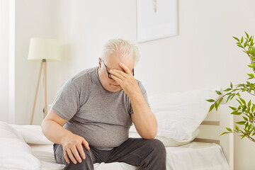 Sad depressed old senior man struggling with insomnia, headache and mental health problems wakes up...