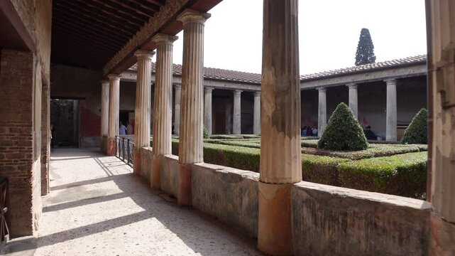 Walking through courtyard of ancient building in Pompeii, one of Italy's best preserved historic sites 

