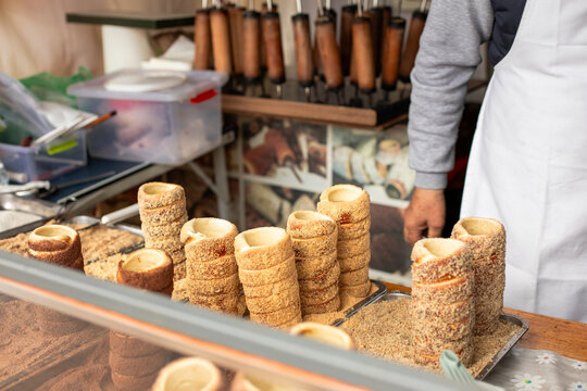 Traditional chimney cakes on display at a street market stall. Chimney cakes with sugar and nuts.