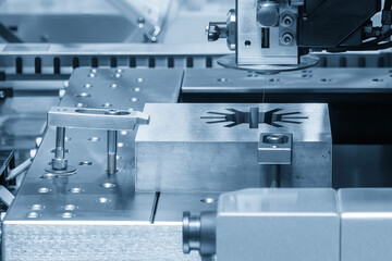The die insert cutting process by wire EDM machine control by CNC program in the light blue scene....