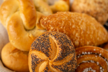 wicker basket overflowing with freshly baked pastries: cheese and poppy seed buns, pretzels, and sweet curd tarts