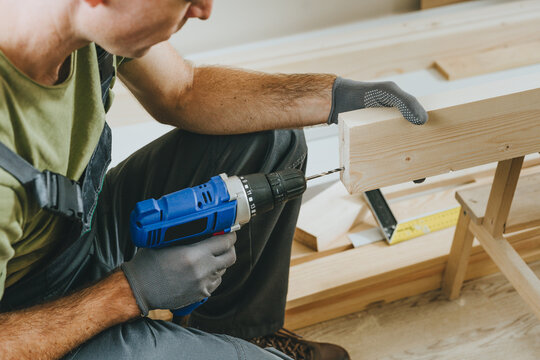 Close up of carpenter drilling a board with a screwdriver in his workshop