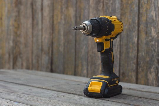 Yellow Cordless power drill on wooden surface for construction, DIY, and home repair projects.