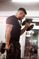 Junger, muskulöser Mann trainiert mit Kurzhantel hellen, seine Oberarme. Pumpen im Fitnessstudio.