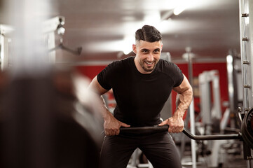 Junger Mann mit dunklen Haaren trainiert im Fitnessstudio. Krafttraining mit Geräten.