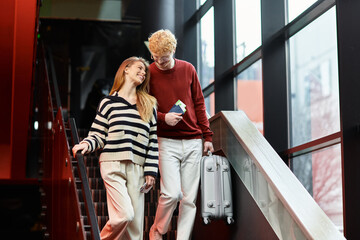 Young couple enjoys romantic moments while arriving at modern hotel in vibrant city