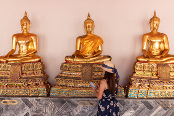 Tourists look at golden Buddha in Temple , Bangkok Thailand