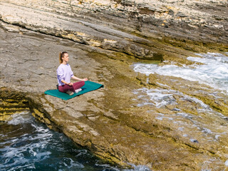 young woman relaxing on rocky cliffs by the sea. Capturing moments of mindfulness, mental wellness, and natural balance with ocean energy
