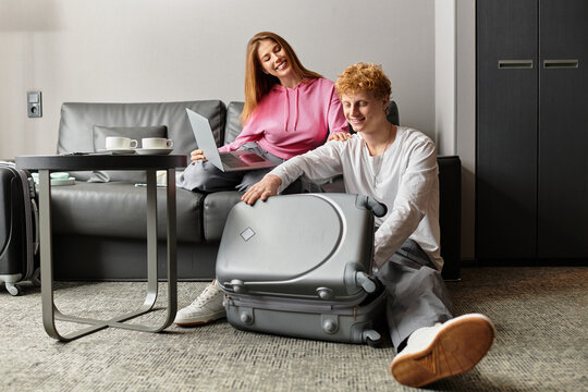 Joyful young couple bonding together in hotel room while packing for their next adventure