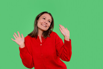 Smiling woman in red sweater joyfully dancing against green backdrop during a vibrant indoor moment