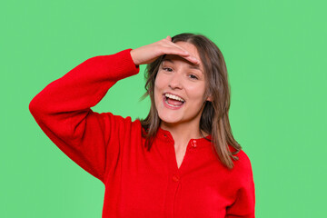 Smiling woman in red sweater saluting against green backdrop during a cheerful moment