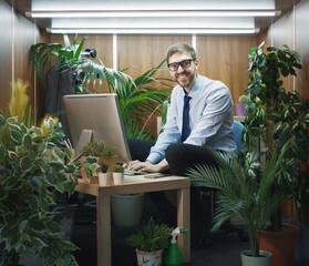 Funny businessman decorating his small office with plants