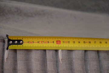 Construction roulette is applied to anger at the folds of the curtains. Curtain with hooks close-up