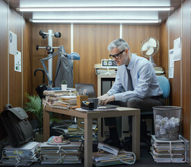 Corporate businessman working in a small messy office