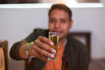Young adult raising a tequila shot celebrating cinco de mayo