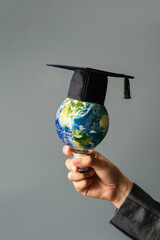 Globe in hand wearing graduation cap. Concept of global education and academic achievement.
